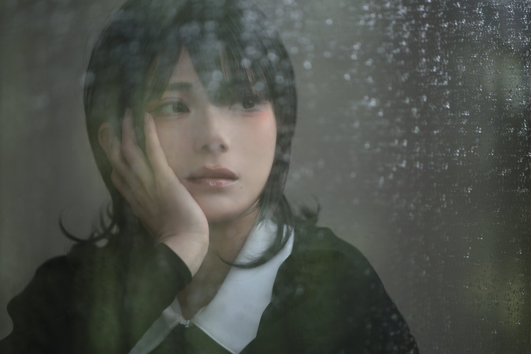 雨粒のついた窓ガラス越しに頬杖をつく人物の扉絵
